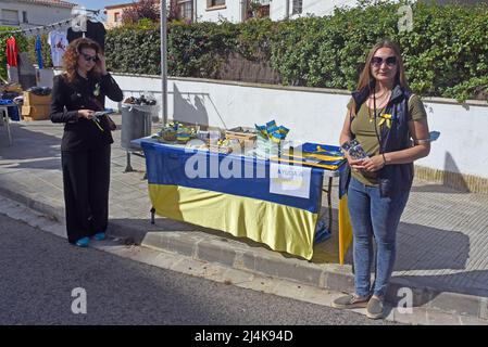 Julia (L) e Mariana (R) due donne rifugiati provenienti dall'invasione russa dell'Ucraina sono al loro tavolo di vendita per gli aiuti all'Ucraina Un gruppo di rifugiati ucraini che vivono nella città di El Vendrell dall'inizio dell'invasione russa ha svolto attività per ricevere aiuto che essi manderà ai loro parenti nel loro paese. Hanno fatto bracciali, cravatte, bandiere e bambole nei colori della bandiera Ucraina (blu e giallo) e il suo prezzo è determinato dal compratore. Nella città di Vendrell ci sono circa 500 rifugiati, di cui 150 sono ragazzi e ragazze. Foto Stock