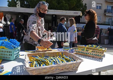 16 aprile 2022, Vendrell, Tarragona, Spagna: Un uomo acquista un braccialetto con i colori della bandiera Ucraina al Vendrell Street Market. Un gruppo di rifugiati ucraini che vivono nella città di El Vendrell dall'inizio dell'invasione russa ha svolto attività per ricevere aiuto che manderanno ai loro parenti nel loro paese. Hanno fatto bracciali, cravatte, bandiere e bambole nei colori della bandiera Ucraina (blu e giallo) e il suo prezzo è determinato dal compratore. Nella città di Vendrell ci sono circa 500 rifugiati, di cui 150 sono ragazzi e ragazze. (Credit Image: © Ramon Costa/SOPA i Foto Stock