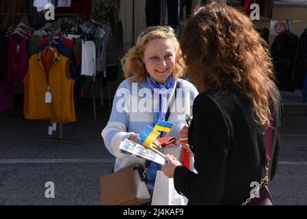 16 aprile 2022, Vendrell, Tarragona, Spagna: Una donna acquista piccole bandiere ucraine al mercato di Vendrell Street. Un gruppo di rifugiati ucraini che vivono nella città di El Vendrell dall'inizio dell'invasione russa ha svolto attività per ricevere aiuto che manderanno ai loro parenti nel loro paese. Hanno fatto bracciali, cravatte, bandiere e bambole nei colori della bandiera Ucraina (blu e giallo) e il suo prezzo è determinato dal compratore. Nella città di Vendrell ci sono circa 500 rifugiati, di cui 150 sono ragazzi e ragazze. (Credit Image: © Ramon Costa/SOPA Images via ZUMA Press Wire Foto Stock