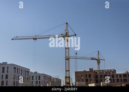 Due gru a torre vicino all'edificio con edificio in cemento in costruzione Foto Stock