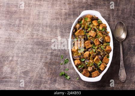 Ripieno vegano con funghi, porri e crostini croccanti su tavola di legno, vista dall'alto, orizzontale, spazio libero. Pasto tradizionale di ringraziamento Foto Stock