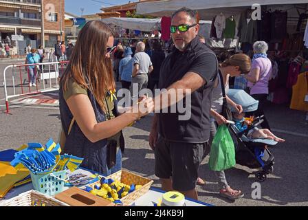 16 aprile 2022, Vendrell, Tarragona, Spagna: Un uomo acquista un braccialetto con i colori della bandiera Ucraina al Vendrell Street Market. Un gruppo di rifugiati ucraini che vivono nella città di El Vendrell dall'inizio dell'invasione russa ha svolto attività per ricevere aiuto che manderanno ai loro parenti nel loro paese. Hanno fatto bracciali, cravatte, bandiere e bambole nei colori della bandiera Ucraina (blu e giallo) e il suo prezzo è determinato dal compratore. Nella città di Vendrell ci sono circa 500 rifugiati, di cui 150 sono ragazzi e ragazze. (Credit Image: © Ramon Costa/SOPA i Foto Stock