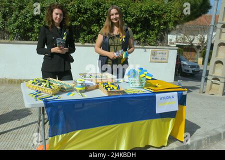 16 aprile 2022, Vendrell, Tarragona, Spagna: Julia (L) e Mariana (R) due donne rifugiati dall'invasione russa dell'Ucraina si trovano al loro tavolo di vendita per gli aiuti all'Ucraina. Un gruppo di rifugiati ucraini che vivono nella città di El Vendrell dall'inizio dell'invasione russa ha svolto attività per ricevere aiuto che manderanno ai loro parenti nel loro paese. Hanno fatto bracciali, cravatte, bandiere e bambole nei colori della bandiera Ucraina (blu e giallo) e il suo prezzo è determinato dal compratore. Nella città di Vendrell ci sono circa 500 rifugiati, di cui 150 sono ragazzi e ragazze Foto Stock