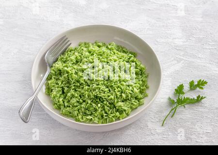 Riso vegano con olio verde in un recipiente bianco su sfondo grigio, spazio libero. Delizioso cibo casereccio Foto Stock