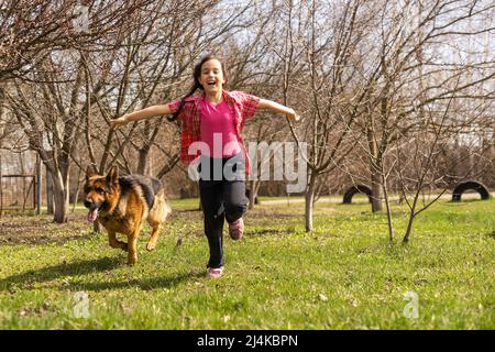 bambina che corre con il suo pastore tedesco animale domestico Foto Stock