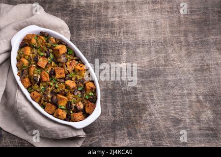 Ripieno vegano con funghi, porri e crostini croccanti su tavola di legno, vista dall'alto, orizzontale, spazio libero. Pasto tradizionale di ringraziamento Foto Stock