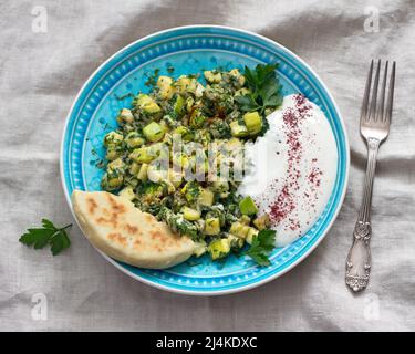 Tradizionale turco fritto uova con zucchine ed erbe con yogurt salsa all'aglio e tortilla fresche su tela grigia da tavola, vista dall'alto. Delizioso lui Foto Stock
