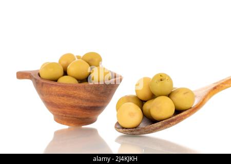 Diverse olive verdi snocciolate in una tazza di legno e con un cucchiaio di legno, macro, isolate su bianco. Foto Stock