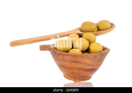 Diverse olive verdi snocciolate in una tazza di legno e con un cucchiaio di legno, macro, isolate su bianco. Foto Stock