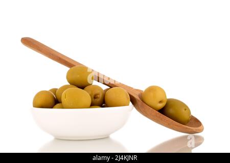 Diverse olive verdi snocciolate in un piattino di ceramica e con un cucchiaio di legno, macro, isolato su bianco. Foto Stock