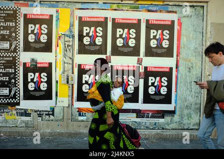 16 aprile 2022, Parigi, Parigi, FRANCIA: Una donna africana che porta un bambino cammina davanti a un poster di uno dei più antichi giornali dell'ala sinistra della Francia, l'humanite. Il poster dice, pas elle, non lei, riferendo a Marine le Pen come presidente della Francia. Le organizzazioni antirazziste e antifasciste, i sindacati e i gruppi della società civile si uniscono a migliaia di manifestanti che denunciano la presenza di Marine le Pen, politico di estrema destra, nel secondo turno delle elezioni presidenziali francesi a Parigi, Francia. Credit: ZUMA Press, Inc./Alamy Live News Foto Stock