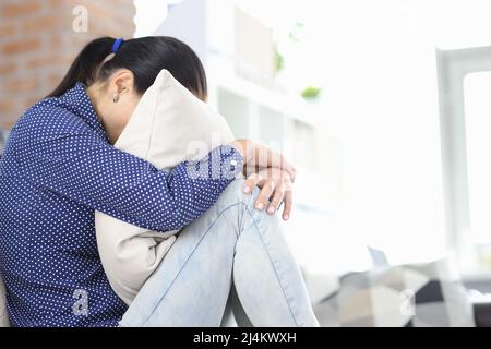 La donna sconvolto si siede con la testa sepolta nel cuscino Foto Stock