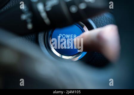 Un primo piano di un dito del conducente che preme un pulsante di accensione senza chiave sul cruscotto di una Toyota CH-R 2021, un'auto ibrida a benzina con carica automatica. REGNO UNITO Foto Stock