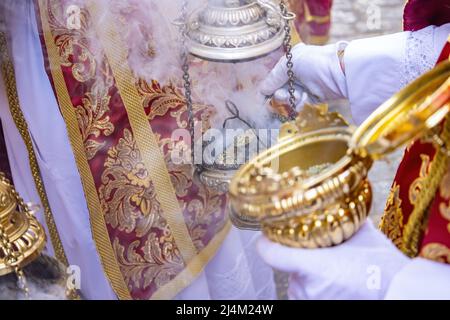 Dettaglio della mano di un ragazzo altare o di un'accolita in una processione della settimana Santa che riempie di incenso uno dei censori Foto Stock