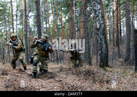 Tre mercenari durante un'operazione speciale nella foresta sul territorio vrezhskaya. Si muovono per unirsi al gruppo principale dopo l'atterraggio dietro li nemico Foto Stock