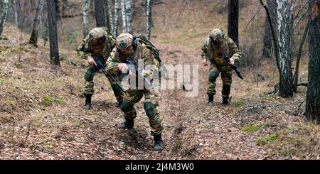 Tre mercenari durante un'operazione speciale nella foresta n autunno sul territorio vrezhskaya. Si spostano per unirsi al gruppo principale dopo l'atterraggio dietro ene Foto Stock