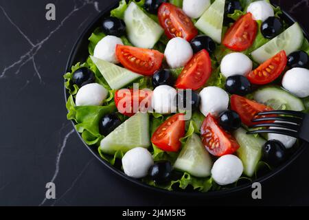 Insalata fresca con cetrioli, pomodori, olive nere e formaggio feta o mozzarella Foto Stock