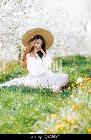 Bella ragazza su un pic-nic primavera nel parco. Brunette con capelli ondulati sullo sfondo della natura estiva. Foto Stock