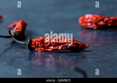 Peperoncino secco rosso su sfondo marmo nero Foto Stock