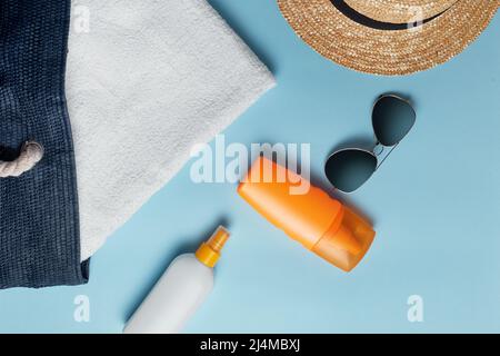 borsa da spiaggia con accessori da spiaggia su sfondo colorato vista dall'alto. Crema solare, asciugamano, occhiali, cappello. Foto Stock