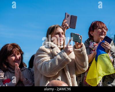Nijmegen, Paesi Bassi. 16th Apr 2022. Le donne ucraine ospitate in città sono viste scattare foto durante il concerto. Sotto il motto, 'music connects people', il musicista Nijmegen Mart Heijmans ha riunito 400 musicisti al Waalkade per cantare l'inno nazionale ucraino e altre canzoni per dimostrare la loro solidarietà con l'Ucraina. Circa 250 di loro sono stati rifugiati ucraini ricevuti negli ultimi mesi nella città. Quattro cantanti ucraini fuggiti, tra cui un cantante lirico, hanno eseguito qualche canzone prima di una folla attenta ed emotiva. Credit: SOPA Images Limited/Alamy Live News Foto Stock