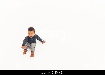 Innocente curioso bambino ragazzo biraciale in piedi su sfondo bianco. Spazio di copia. Foto di alta qualità Foto Stock