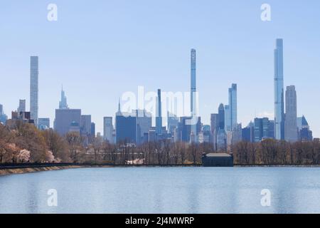 Panorama dello skyline della fila di miliardari visto attraverso il bacino idrico di Central Park con un cielo blu chiaro Foto Stock