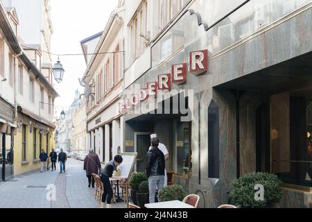 Strasburgo, Francia - 11 apr 2022: Cartello Floderer sopra l'iconico ristorante francese con capo che parla con il fornitore all'aperto, mentre il lavoratore pulisce la segnaletica del menu Foto Stock