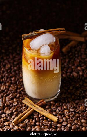 Caffè latte ghiacciato. Tazza di caffè latte ghiacciato, tè al latte su sfondo di semi di caffè scuri Foto Stock