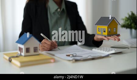 Agente immobiliare tenendo modello di casa al suo cliente dopo la firma contratto di contratto in ufficio, concetto per il bene immobile, casa in movimento o affitto Foto Stock
