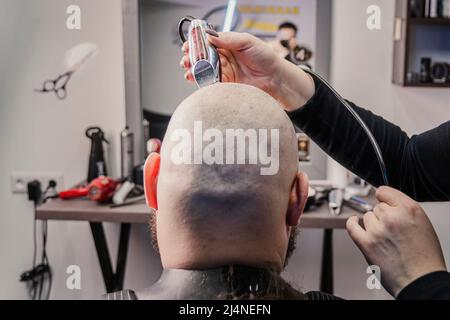 L'uomo caucasico di mezza età sta tagliando i propri capelli con un rasoio elettrico. Foto Stock