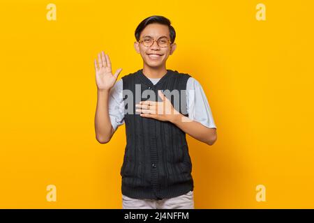 Giovane asiatico sorridente e saluto isolato su sfondo giallo Foto Stock