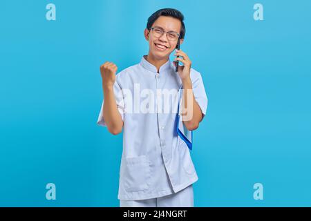 Allegro bel maschio infermiere tenere appunti e parlare sul cellulare su sfondo giallo Foto Stock