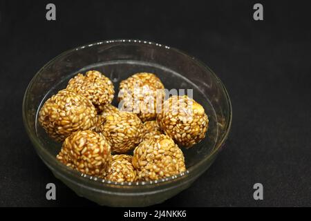 Le palle di sesamo dolci sono in una tazza. Su sfondo nero Foto Stock