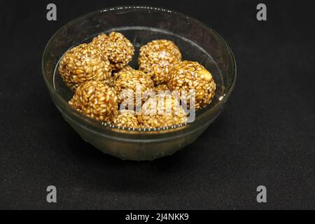 Le palle di sesamo dolci sono in una tazza. Su sfondo nero Foto Stock