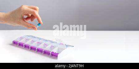 Banner con donna mano che prende pillola, vitamina da caso, scatola. Promemoria e organizzatore per il farmaco quotidiano. Concetto di assistenza sanitaria e medicina. Spazio di copia. Foto di alta qualità Foto Stock