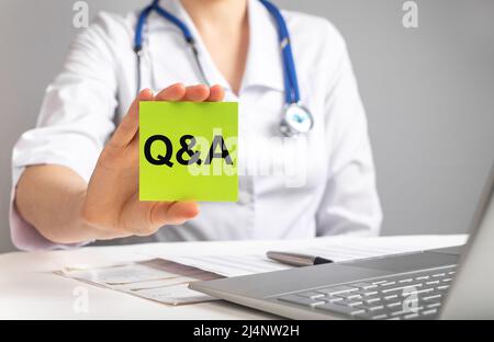 Tessera medico con lettere q A. FAQ in medicina e concetto di assistenza sanitaria. Donna in camice da laboratorio che risponde ai pazienti domande online. Foto di alta qualità Foto Stock