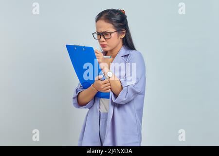 Ritratto di giovane donna asiatica di affari che concentra le note di pianificazione di scrittura che fanno la strategia di vendite isolato su sfondo viola Foto Stock