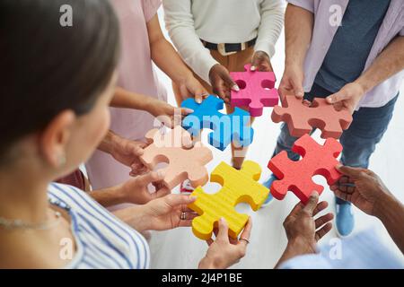 Team di giovani creativi diversi che collegano pezzi colorati di puzzle jigsaw Foto Stock