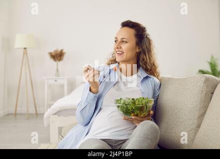 La donna incinta che mangia molte verdure diverse durante la gravidanza gode di insalata verde fresca a casa. Foto Stock