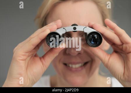 guardare attraverso il binocolo su sfondo grigio nero con le persone che hanno una foto di scorta Foto Stock