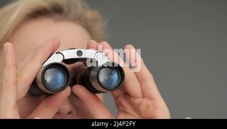 guardare attraverso il binocolo su sfondo grigio nero con le persone che hanno una foto di scorta Foto Stock