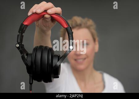 cuffie che ascoltano musica con sfondo grigio con persone che condividono le immagini Foto Stock