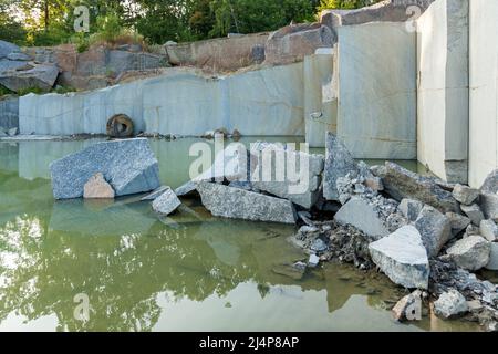 Cava di granito con grandi blocchi di granito abbandonato cava di granito con acqua piovana. Estrazione di granito in una cava. Foto Stock