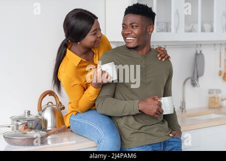 Amorevole coppia afroamericana che beve caffè insieme in cucina interna Foto Stock