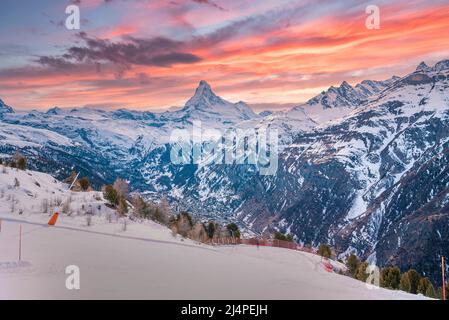 Vista panoramica della catena montuosa innevata contro il cielo nuvoloso durante il tramonto nelle alpi Foto Stock