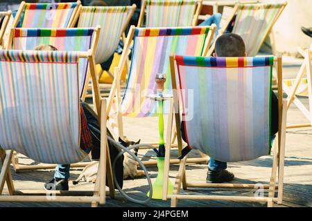La gente sta fumando un hookah che si siede in un chair.Focus su hookah Foto Stock