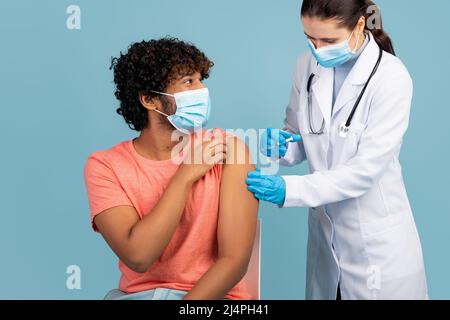 L'uomo curly è stato vaccinato contro il coronavirus su blu Foto Stock