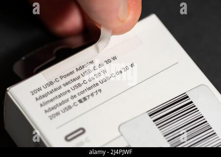 Man's hand close up apertura di un nuovo adattatore di alimentazione USB-C da 20 watt Apple Inc con confezione originale Foto Stock
