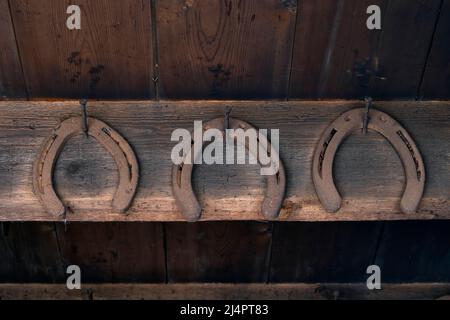 I vecchi ferro di cavallo arrugginiti d'epoca appesi sul muro di un fienile come simbolo di fortuna Foto Stock